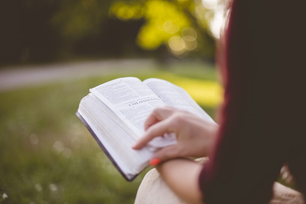 A woman flipping through a bible reading outside.